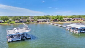 A lakeside property with a dock, a covered boat launch, and a small boat.