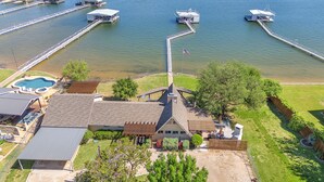 A residential property with a large house, a swimming pool, and a dock extending into a lake.