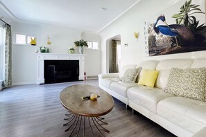 Un salon avec une cheminée, un canapé, une table basse ronde et un tableau accroché au mur.