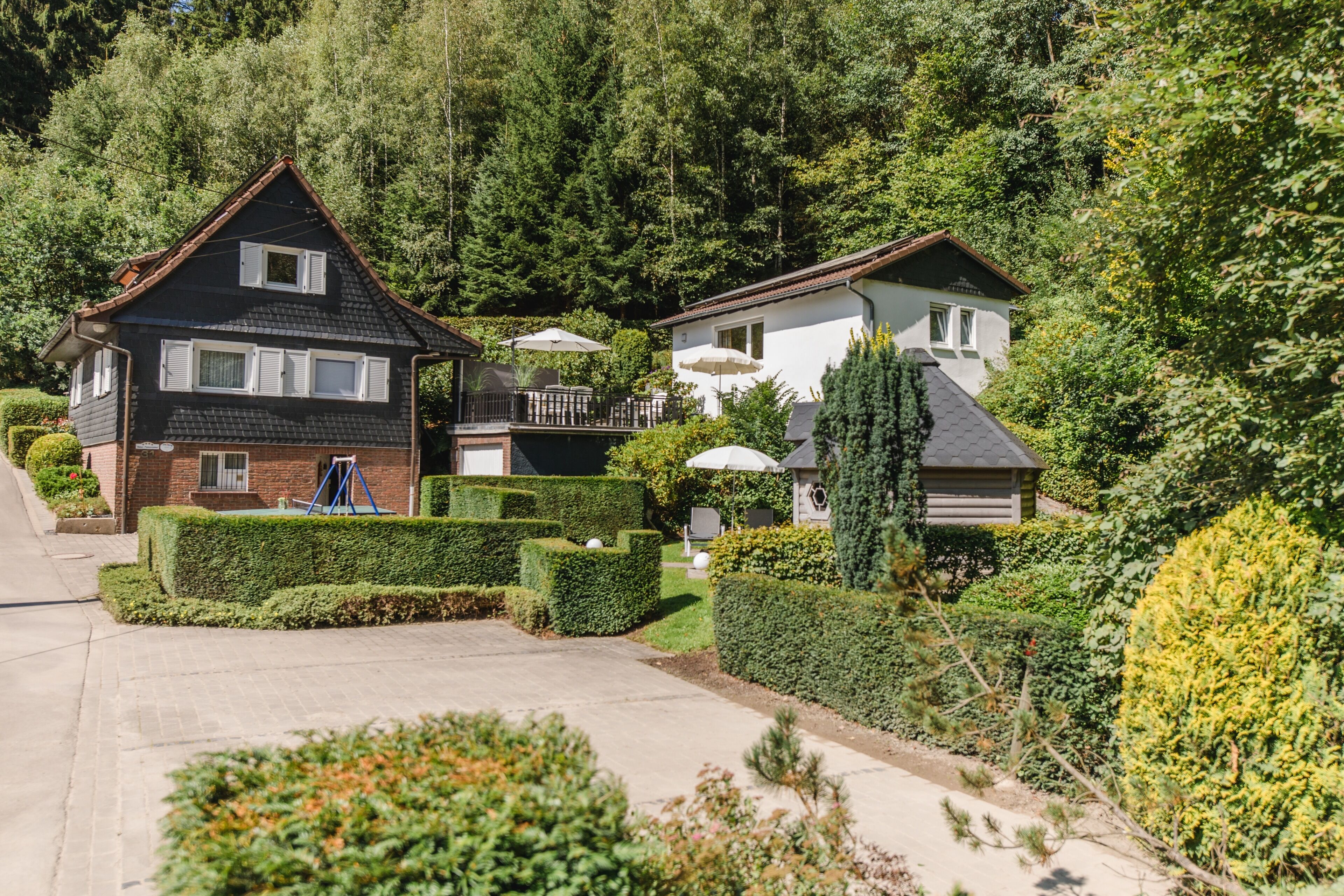 Uma área residencial com duas casas, um jardim bem cuidado e uma entrada livre.
