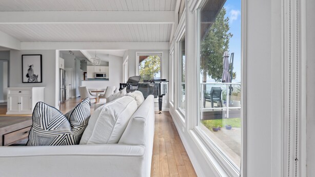 Ein geräumiger Wohnbereich mit einem weißen Sofa, einem Esstisch und einer Küche im Hintergrund.