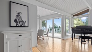 Ein geräumiges Wohnzimmer mit Klavier, einem Zebra-Kunstwerk und einem Essbereich mit Tisch und Stühlen.