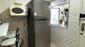 Eine kompakte Küche mit Kühlschrank, Mikrowelle und einer kleinen Essecke mit Stuhl und Tisch.