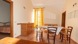 Un comedor con una mesa, sillas, un armario de madera y una ventana con cortinas.