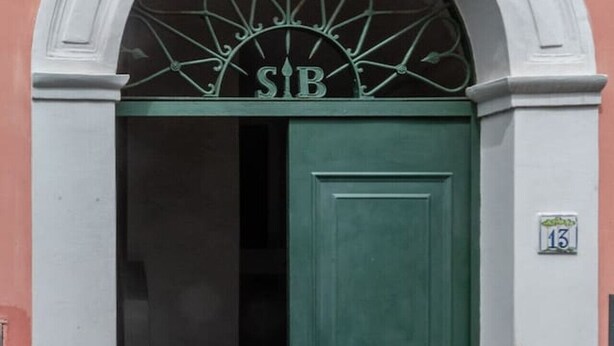 Una puerta verde con las letras “SIB” en la parte superior, ubicada en un vano de arco.