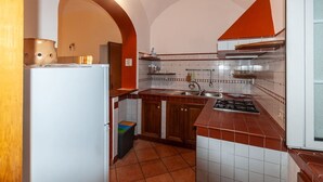 Una cocina con un refrigerador blanco, gabinetes de madera, salpicadero de azulejos y una estufa.