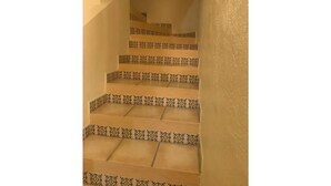 Una escalera con peldaños estampados y paredes color beige.