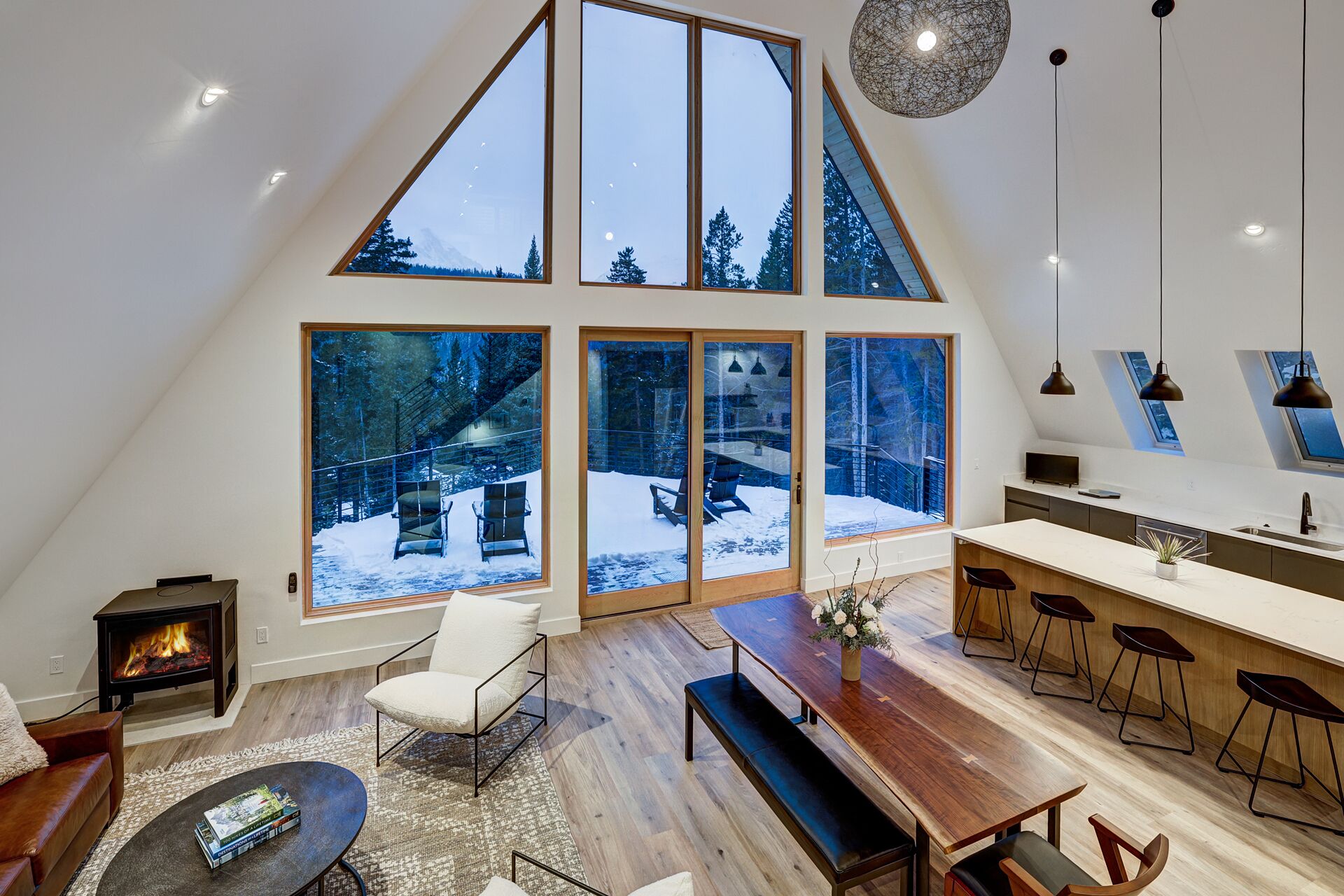 Un loft espacioso con un tragaluz grande, una chimenea acogedora y una cocina moderna con taburetes de bar.