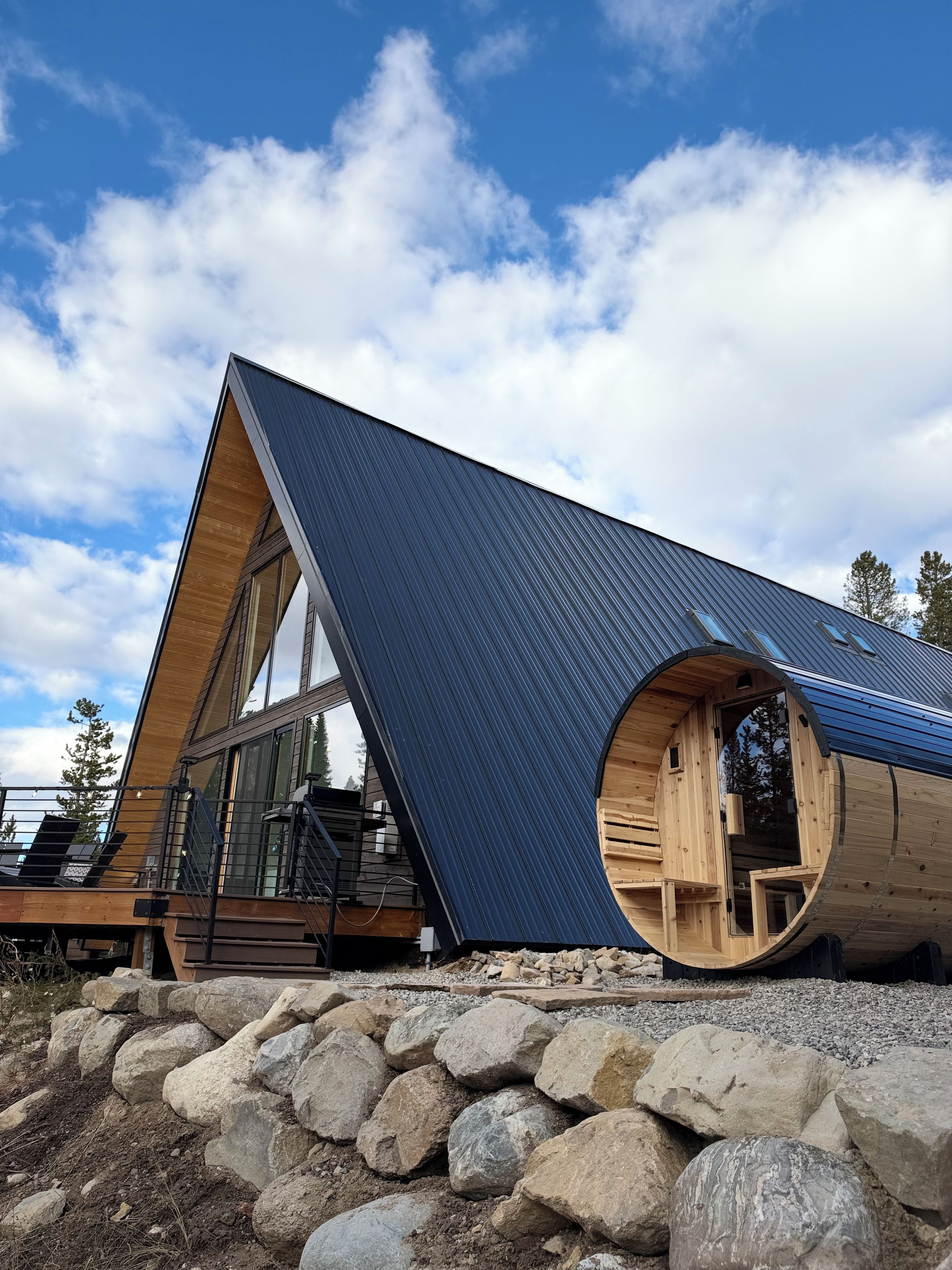 Una cabaña moderna con techo inclinado, ventanas amplias y una estructura circular de madera.