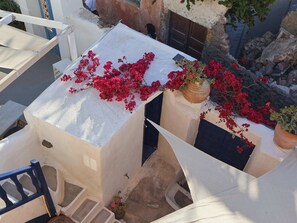 Un bâtiment blanc doté d’un balcon, d’une plante en pot et d’un escalier.