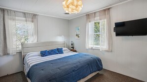 Ein Schlafzimmer mit Bett, Vorhängen, Fernseher und Deckenleuchte.
