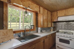 A kitchen with wooden cabinets, a stainless steel sink, a coffee maker, and a stove.