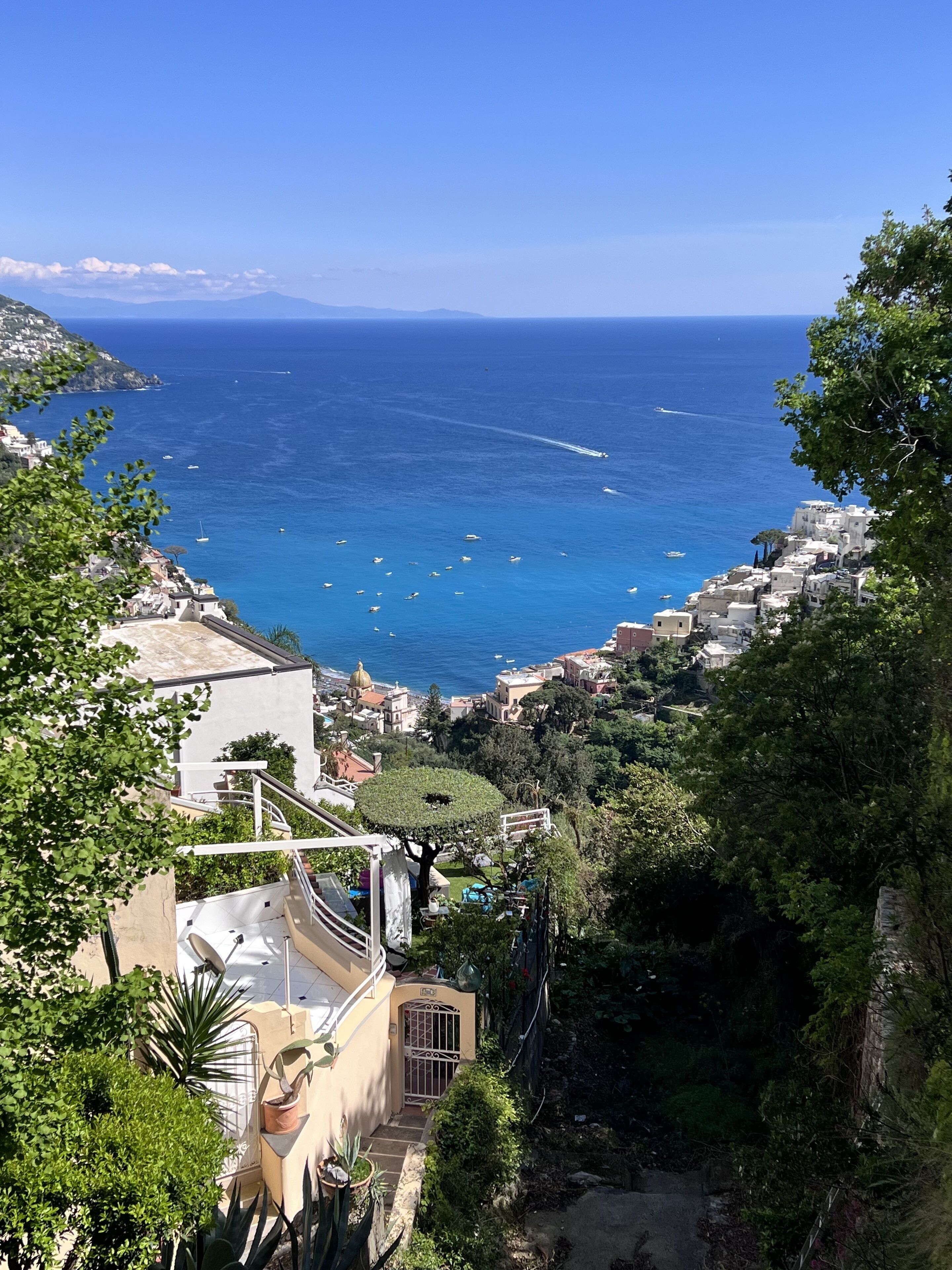 Un pueblo costero con edificios que dan al mar, cielo despejado y barcos en el agua.