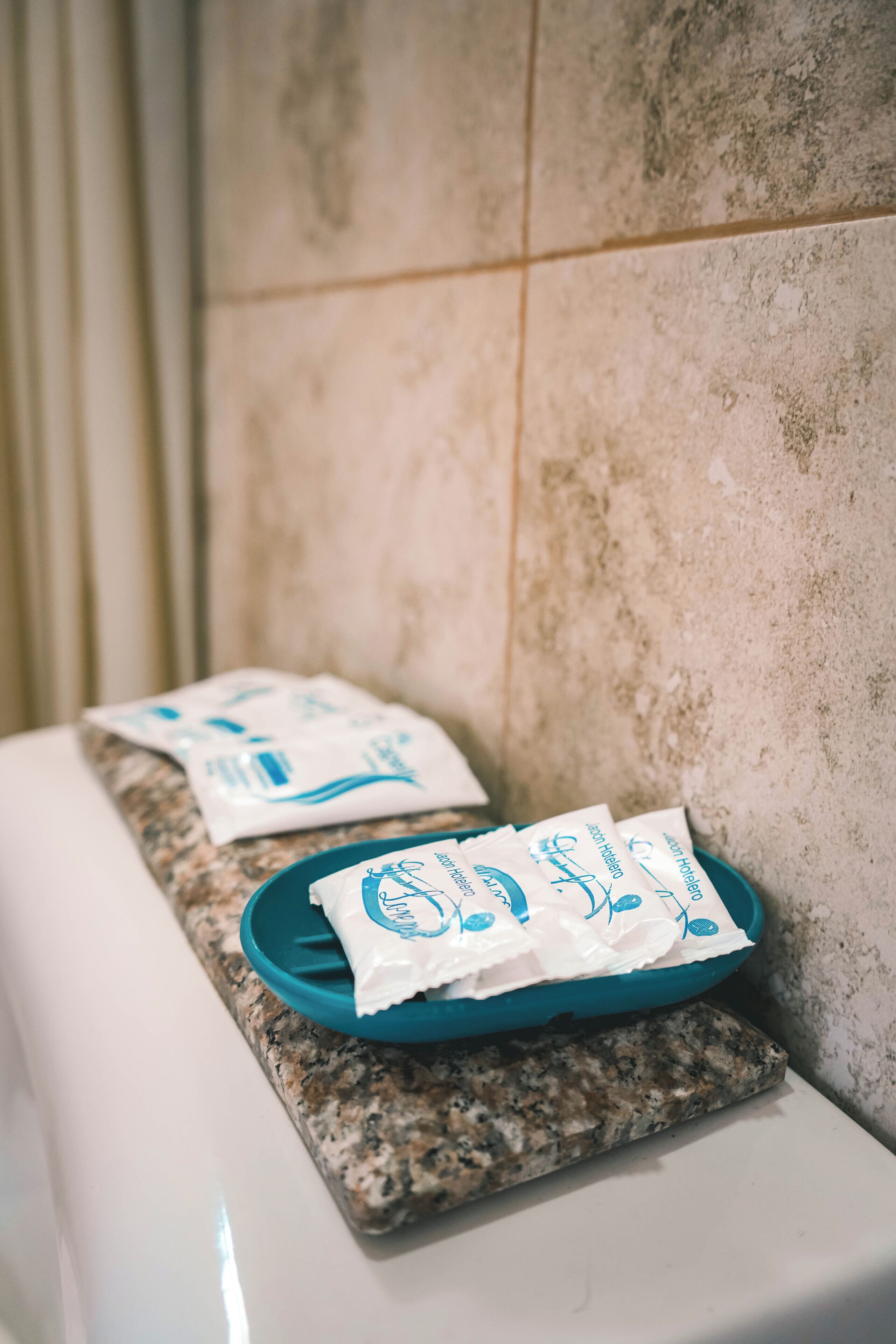 A bathroom with a granite countertop, a white sink, and a blue tray holding toiletries.