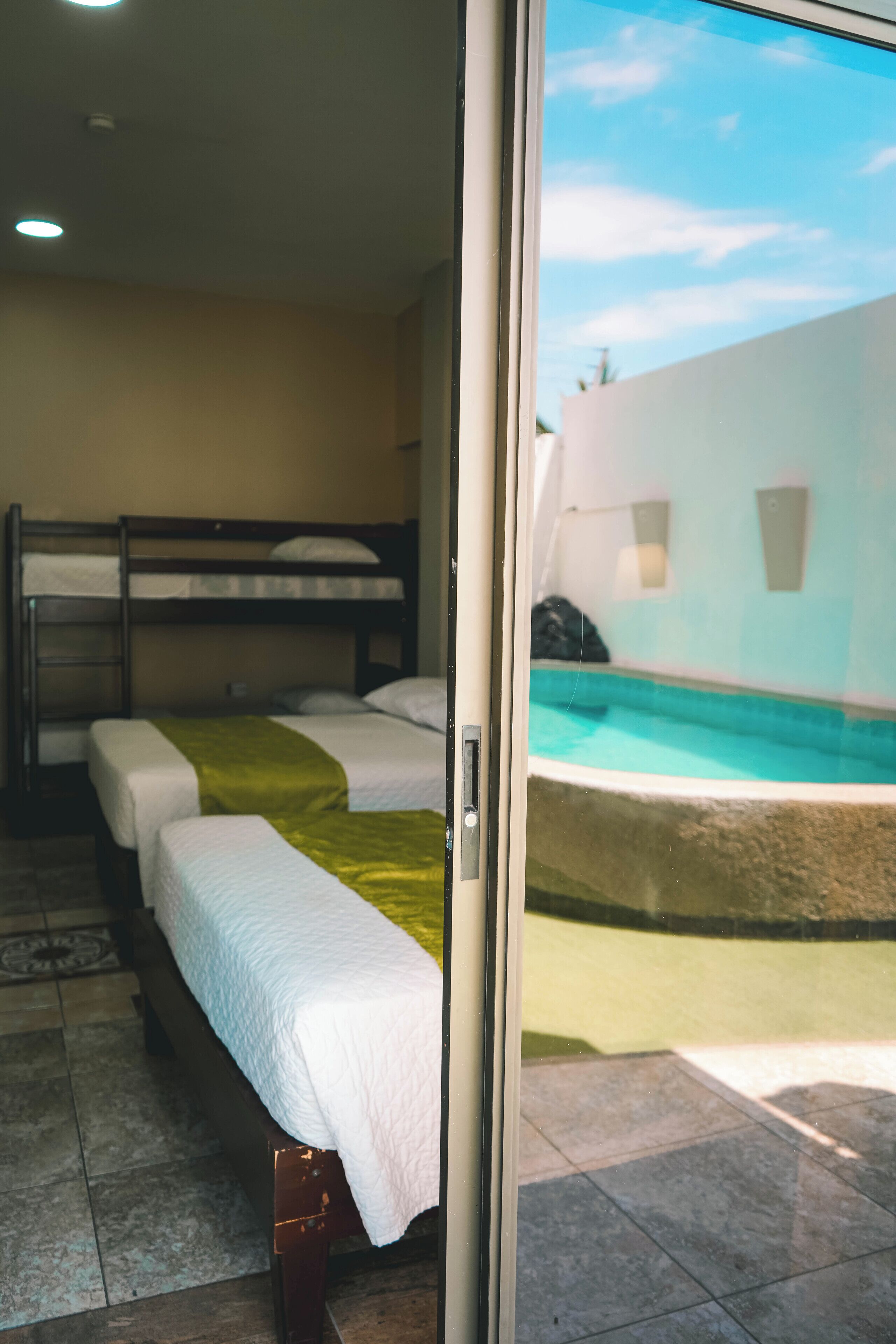 A room with bunk beds, a sliding glass door leading to a pool area.