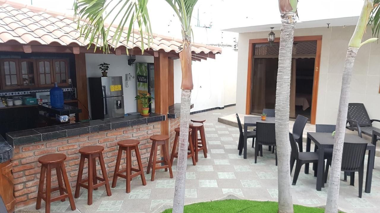 An outdoor patio area with a bar, seating, and palm trees.