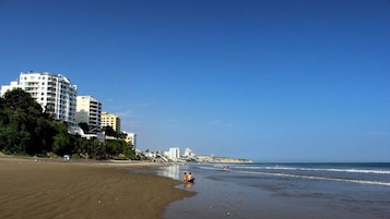Una playa con un complejo de edificios al fondo.