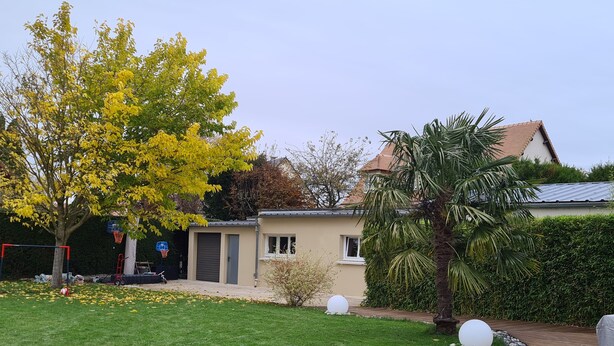 En boligejendom med en velplejet græsplæne, en basketballkurv og en træterrasse.
