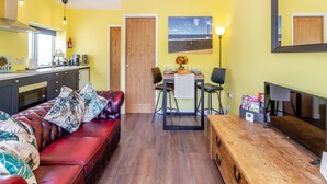 A compact living space with a kitchenette, a dining area, and a seating area with a sofa and chairs. - 1 bedroom accommodation in Ammanford (Ammanford)