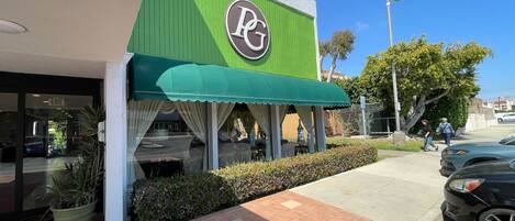 Un restaurante con toldo verde y logotipo PG.