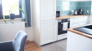 A modern kitchen with white cabinetry, a wooden countertop, and a window with blue curtains.