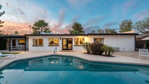 Et moderne hus med swimmingpool, terrasse og veloplyst indgang.