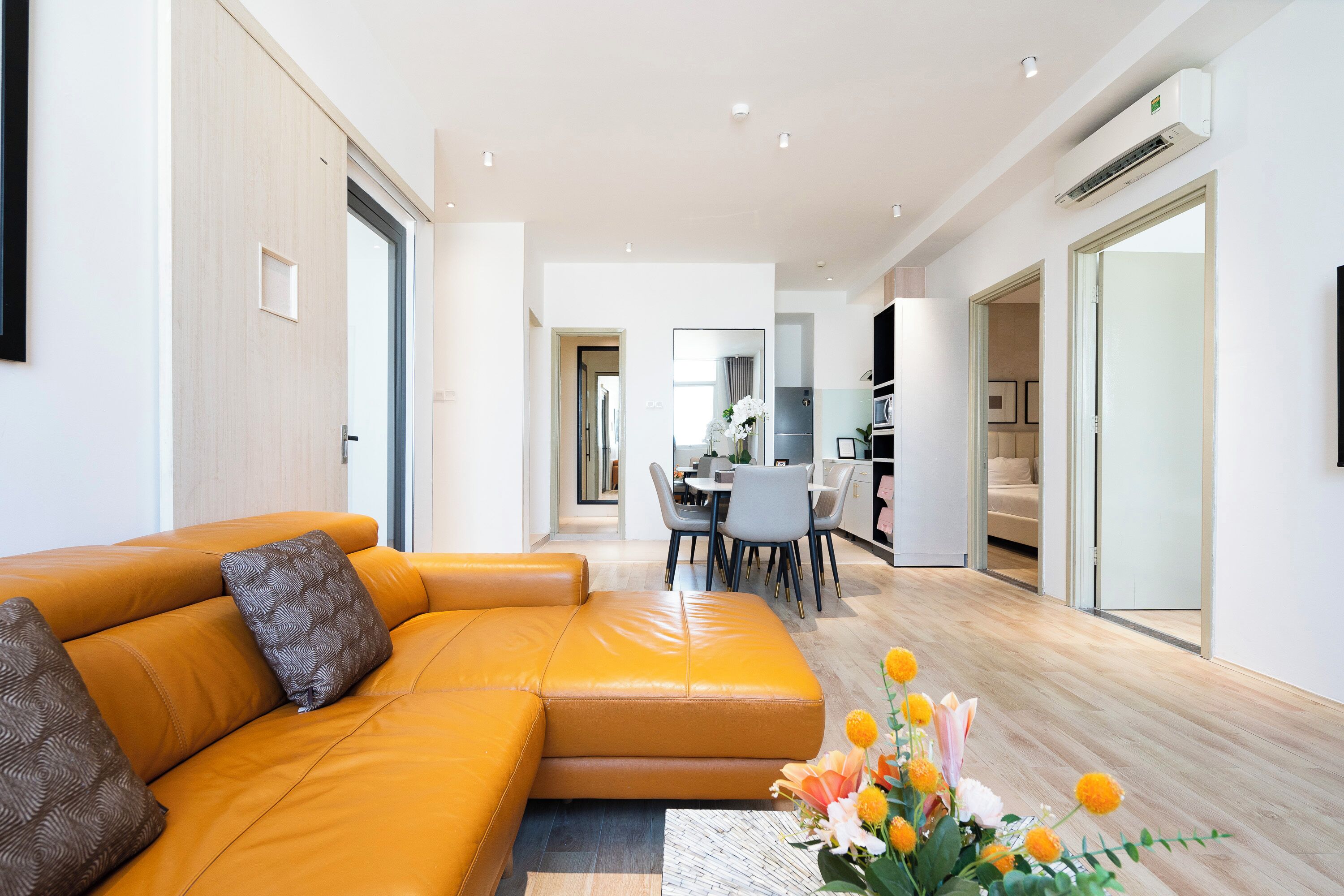 Een moderne woonkamer met een leren bank, een eethoek en een keuken op de achtergrond.