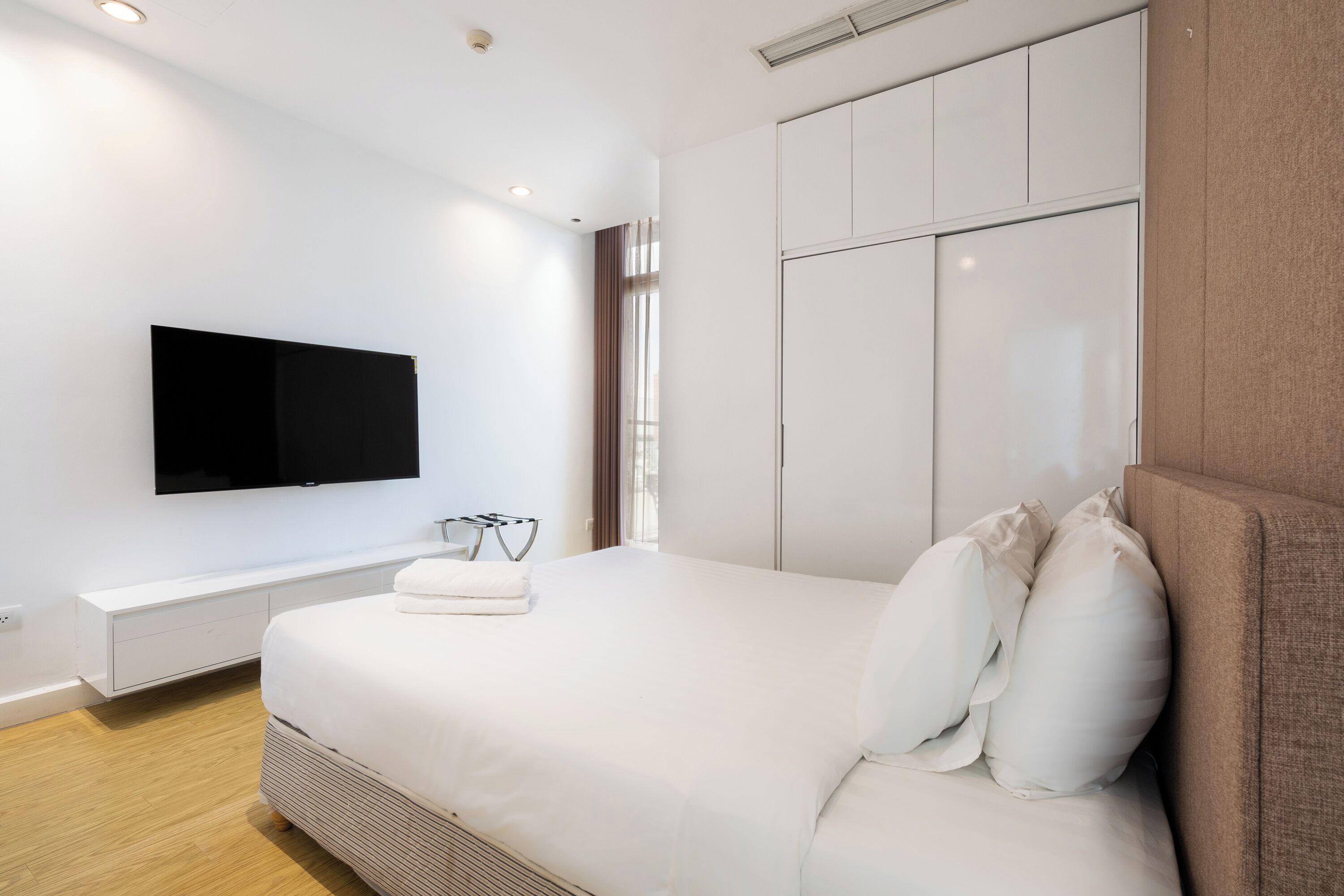 Une chambre d’hôtel moderne dotée d’un grand lit, d’un téléviseur à écran plat fixé au mur et d’une armoire intégrée.