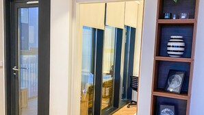 A modern interior with a wooden floor, a sliding glass door leading to a balcony, and a shelf with framed items. - Luxurious modern apartment in Reykjavik with ocean view! (Reykjavík)