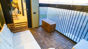 A balcony with a wooden floor, a bed, and a small table. - Luxurious modern apartment in Reykjavik with ocean view! (Reykjavík)