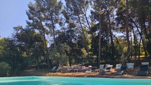 Una piscina limpia con sillas de descanso y una pared de piedra.