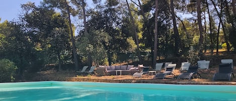 A clear swimming pool with lounge chairs and a stone wall.