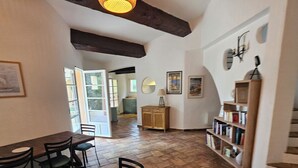 Un comedor con una mesa y sillas de madera, una lámpara colgante, una estantería y una escalera.