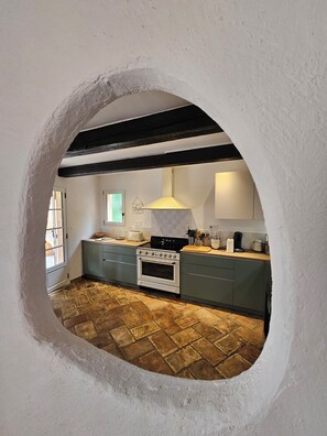 Uma cozinha com piso de pedra, fogão branco e armários verdes.