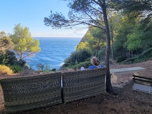 A wicker chair overlooking a coastal view with a clear sky.
