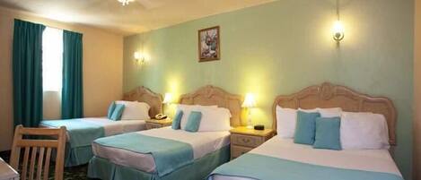 A hotel room with two single beds, a wooden chair, a desk, and a ceiling fan.
