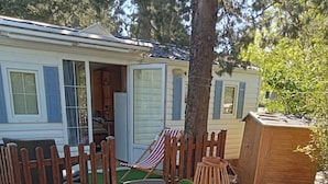 Un patio con una mesa, sillas, una cerca de madera y un cobertizo pequeño.