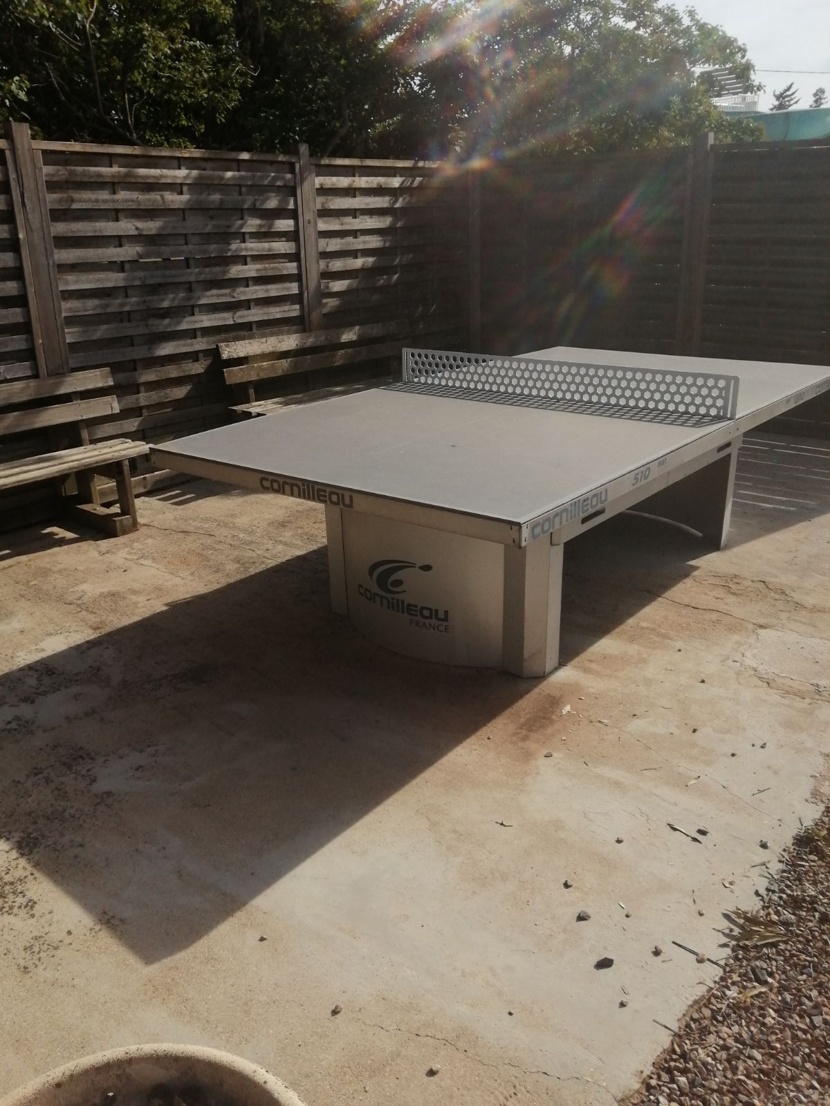 A ping pong table with the brand 'Cornilleau' and model number '510' in a backyard setting.