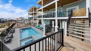 A multi-story building with a pool area, outdoor seating, and a deck. - New luxury ocean front w/Heated private pool, Elevator, 8 Bed/8 Bath (Holden Beach)