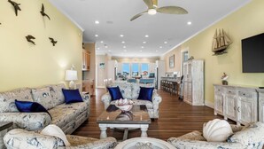 A spacious living room with patterned sofas, a coffee table, and a dining area in the background. - New luxury ocean front w/Heated private pool, Elevator, 8 Bed/8 Bath (Holden Beach)