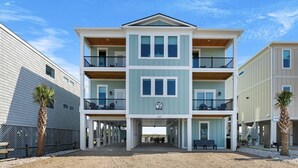 A multi-story building with a covered entrance and a balcony on each floor. - New luxury ocean front w/Heated private pool, Elevator, 8 Bed/8 Bath (Holden Beach)