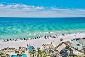 A beach with clear turquoise water, a sandy shore, and several beach umbrellas. - Luxury Beach House ★ Walk to Beach ★ Steps to Pool ★ Private Beach Pavilion (Miramar Beach)