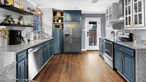 A modern kitchen with granite countertops, stainless steel appliances, and blue cabinetry. - Relaxing Oasis - Walk to Lake Austin, Pet Friendly
 (Austin)