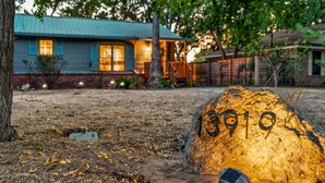 A house with a blue roof and a number 13910 carved into a rock in the yard. - Relaxing Oasis - Walk to Lake Austin, Pet Friendly
 (Austin)