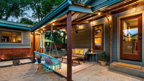 A covered outdoor seating area with a swing chair, a sofa, and a small table. - Relaxing Oasis - Walk to Lake Austin, Pet Friendly
 (Austin)