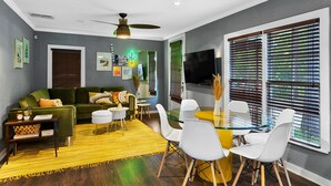 A modern living room with a green sofa, white chairs, a glass coffee table, and a yellow rug. - Relaxing Oasis - Walk to Lake Austin, Pet Friendly
 (Austin)