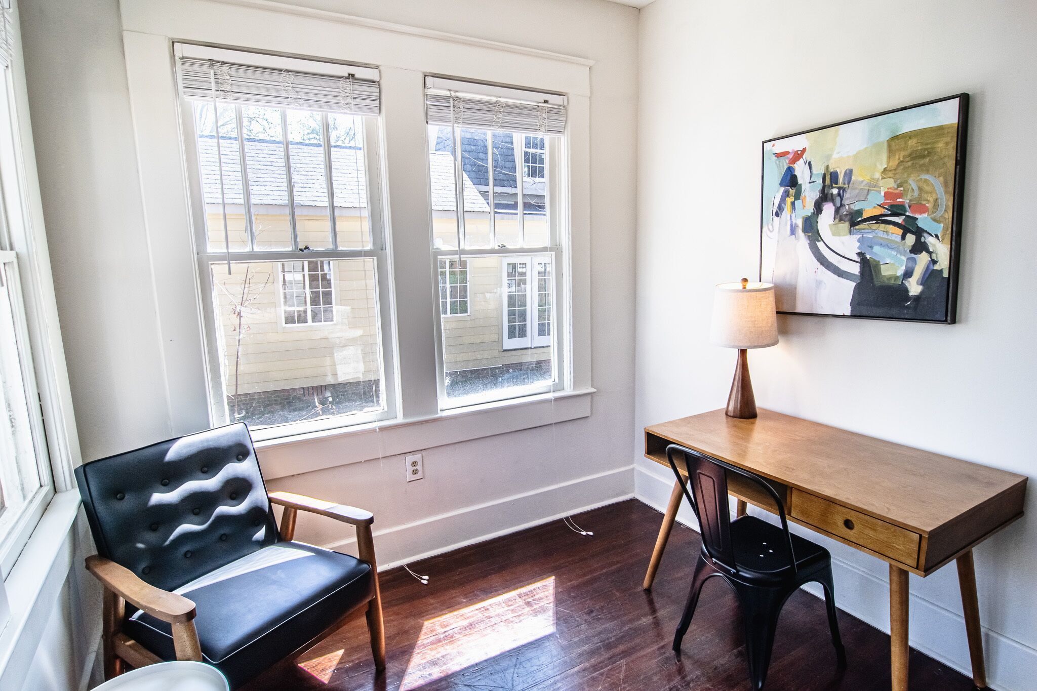 Une pièce comprenant un bureau, deux chaises, une lampe et un tableau accroché au mur.