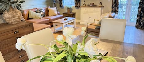 Un salon avec un canapé, une table basse et un vase rempli de fleurs blanches.