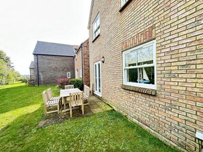 A brick house with a patio, a table, and chairs.