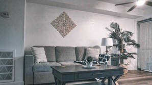 A modern living room with a grey sofa, a dark coffee table, and a decorative wall piece.